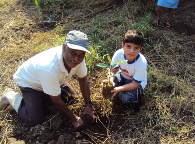 Ranger helps a child plant a tree in the Atlantic Rainforest