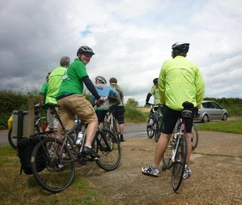 Photograph of cyclists, storm clouds looming