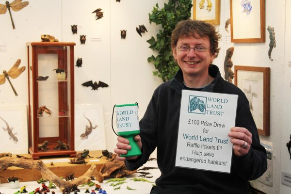 John Noble-Milner holds up a WLT collection box and raffle poster.