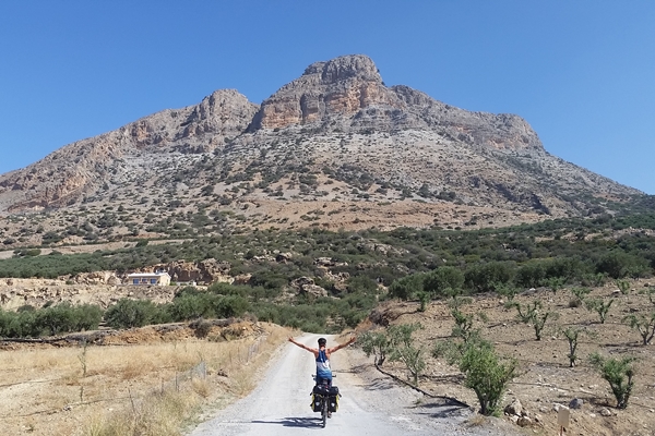 No hands! Cyclist on the road in Crete, mountain in background