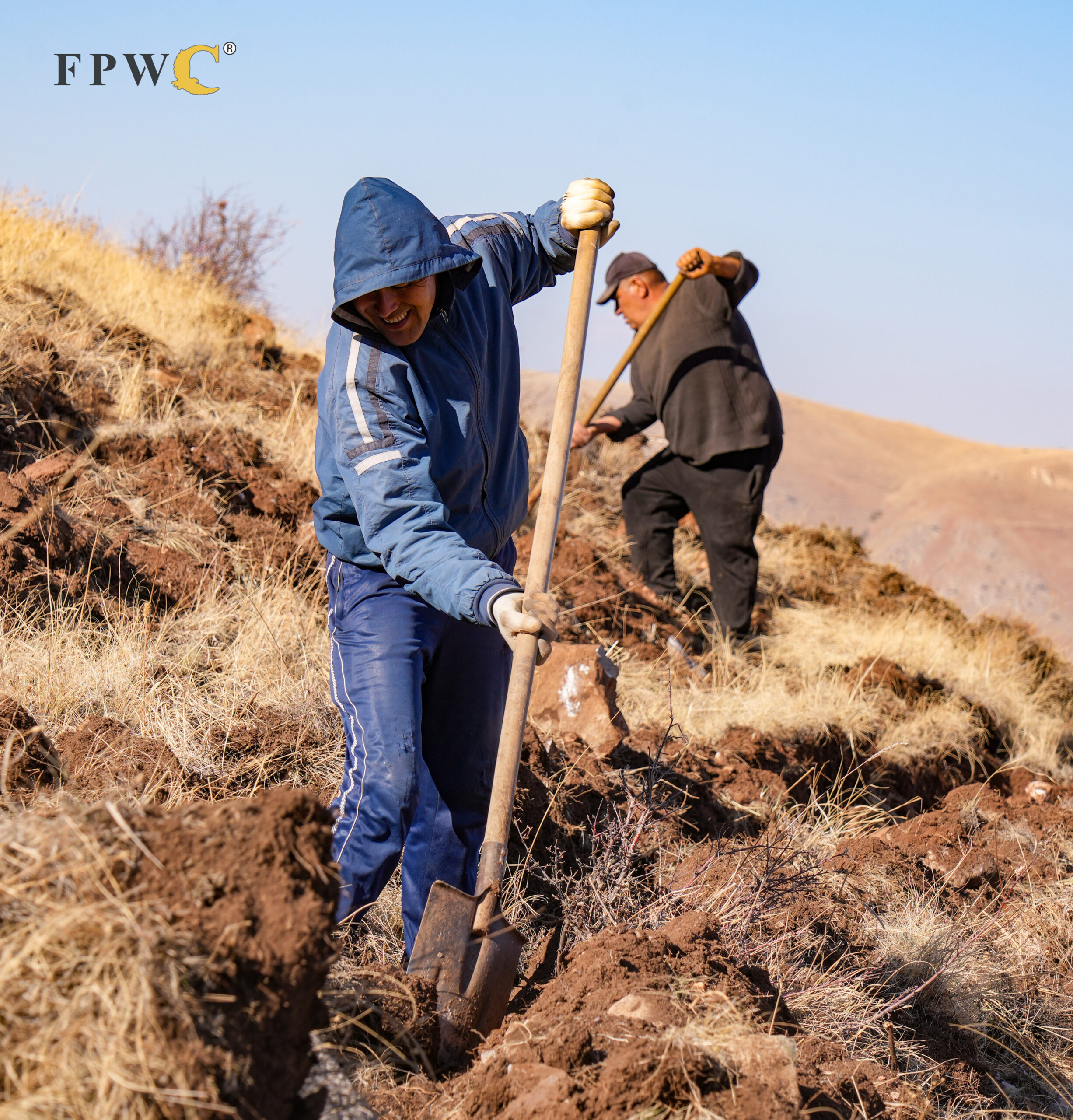 Two volunteers prepare the soil for planting
